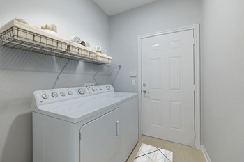 A white washing machine sits in a laundry room.